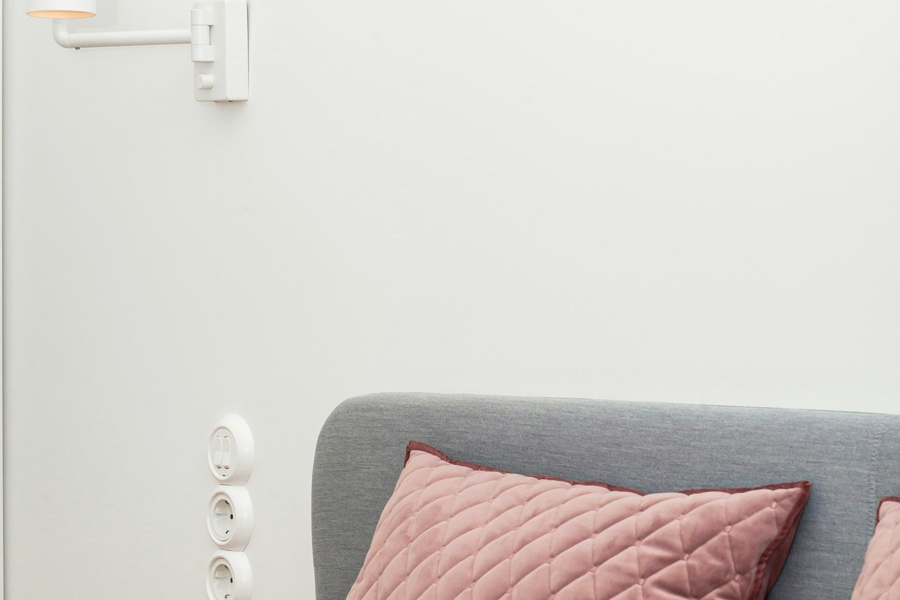Bed with pink cushions and a deep red throw