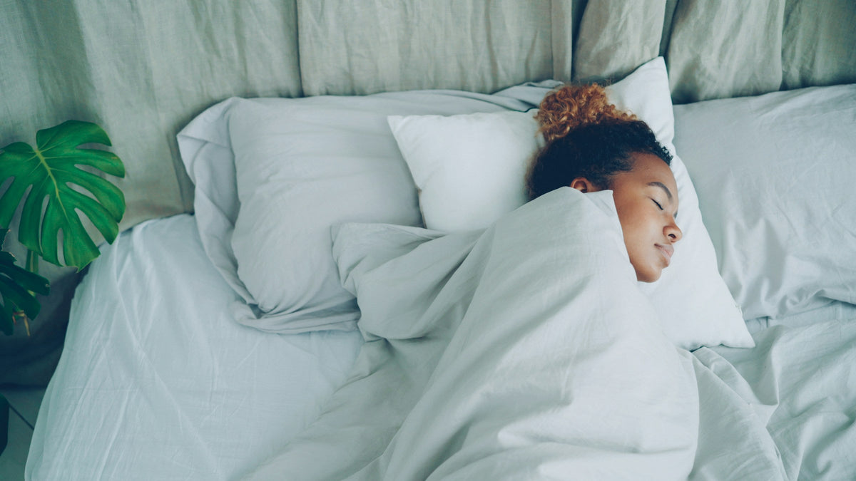 Woman sleeping peacefully in white cotton sheets