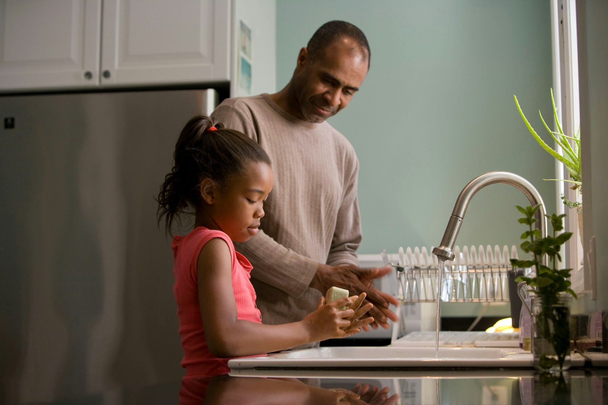 Child washing hands at the sink with a parent