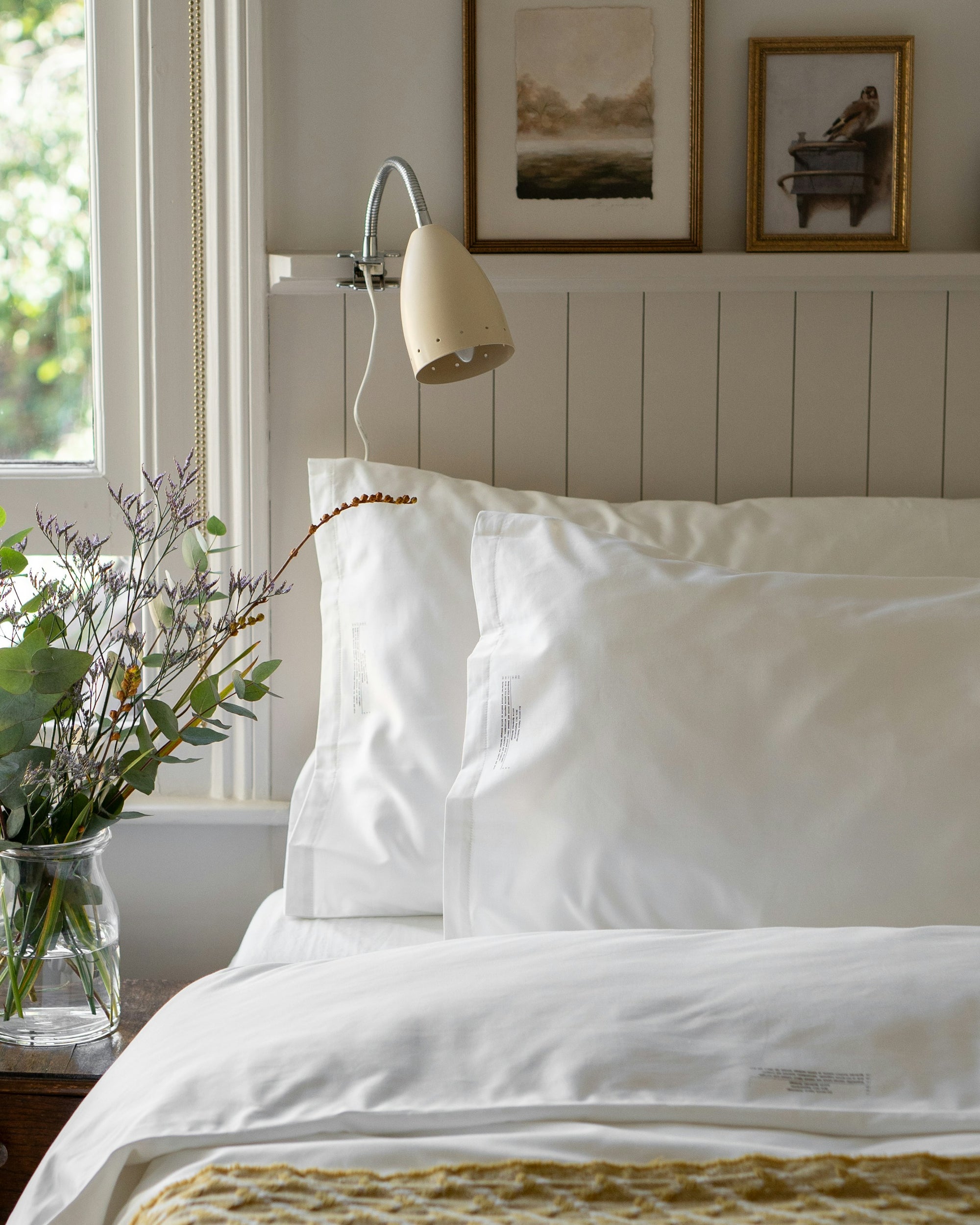 White comforter on a bed with a knitted throw at the foot