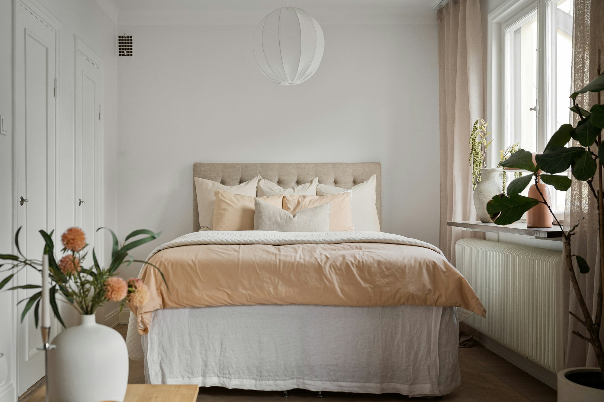 Bright bedroom with a freshly made bed in soft peach cotton sheets