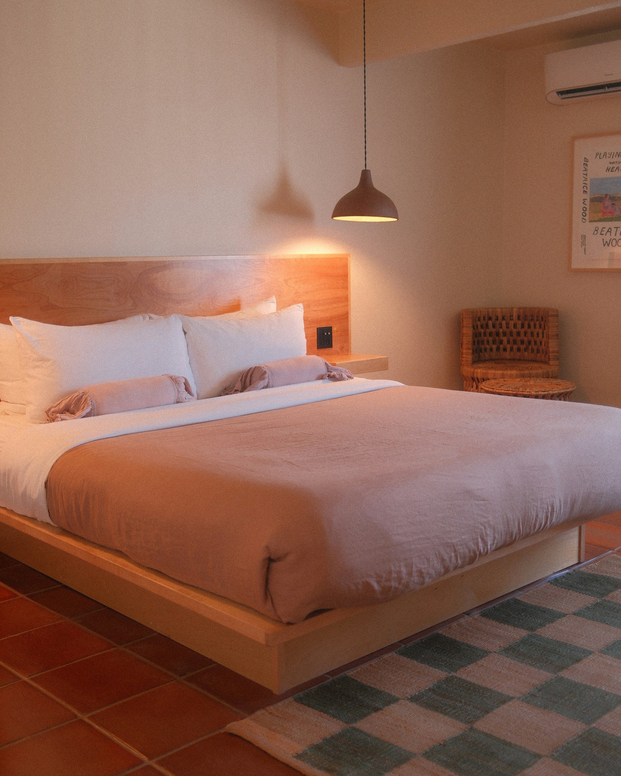 Bed with soft pink cotton sheets in warm evening lamp light